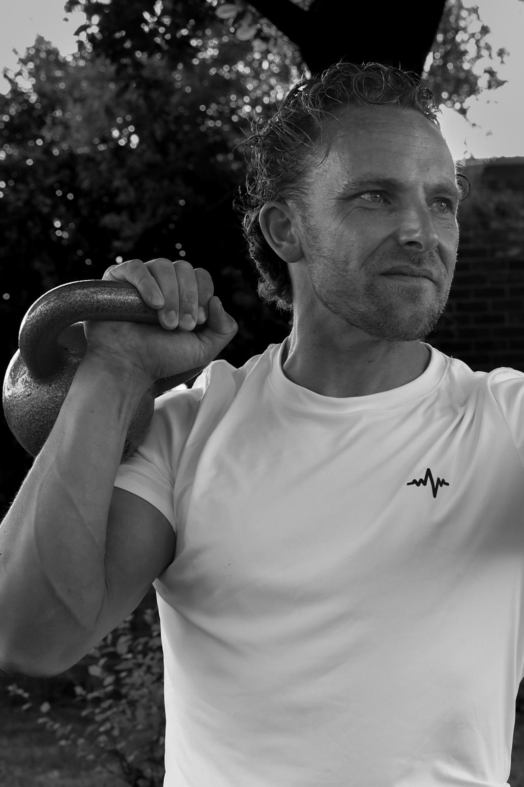 Personal trainer met kettlebell front rack squat positiie